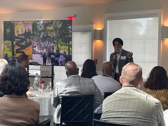 Professional speaker in turban addressing seated audience at indoor conference room.