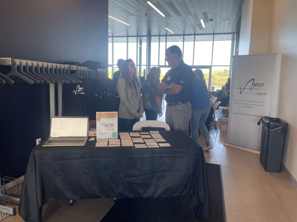 Professional networking event with registration table, laptop, name tags, and attendees conversing.