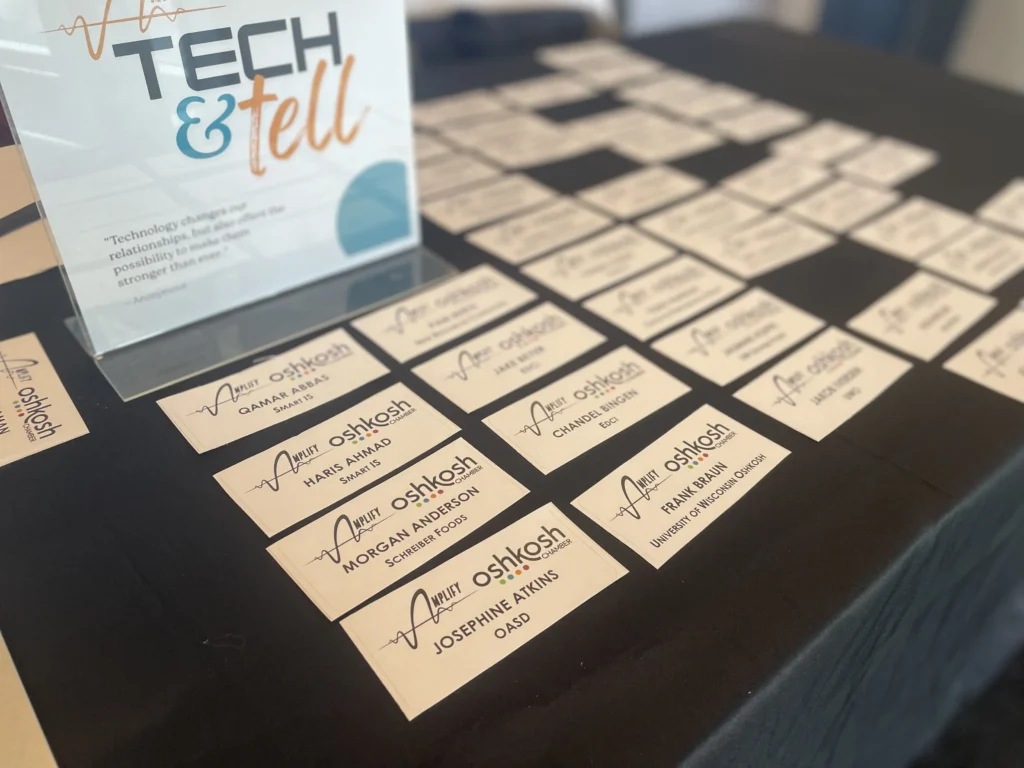 Name tags arranged on a black tablecloth with a "Tech & Tell" event sign.