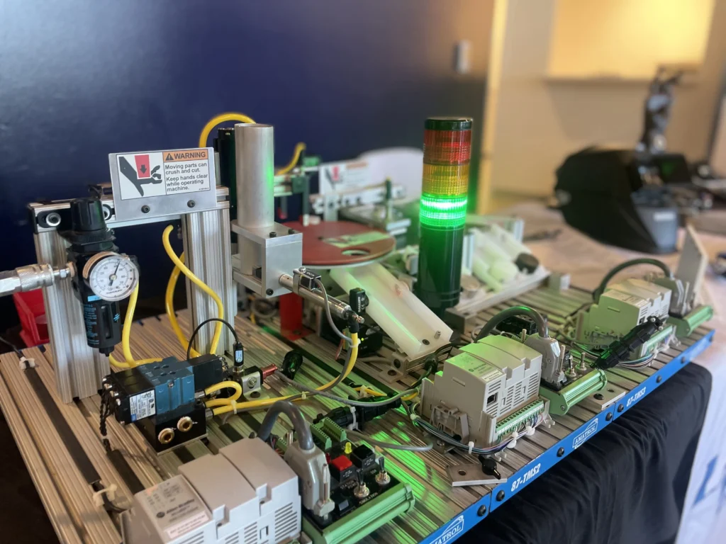 Industrial automation setup with sensors, control modules, warning sign, and green indicator light.