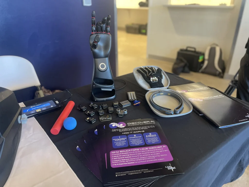 Display of advanced prosthetic hand, wearable tech devices, and informational brochures on a black tablecloth.