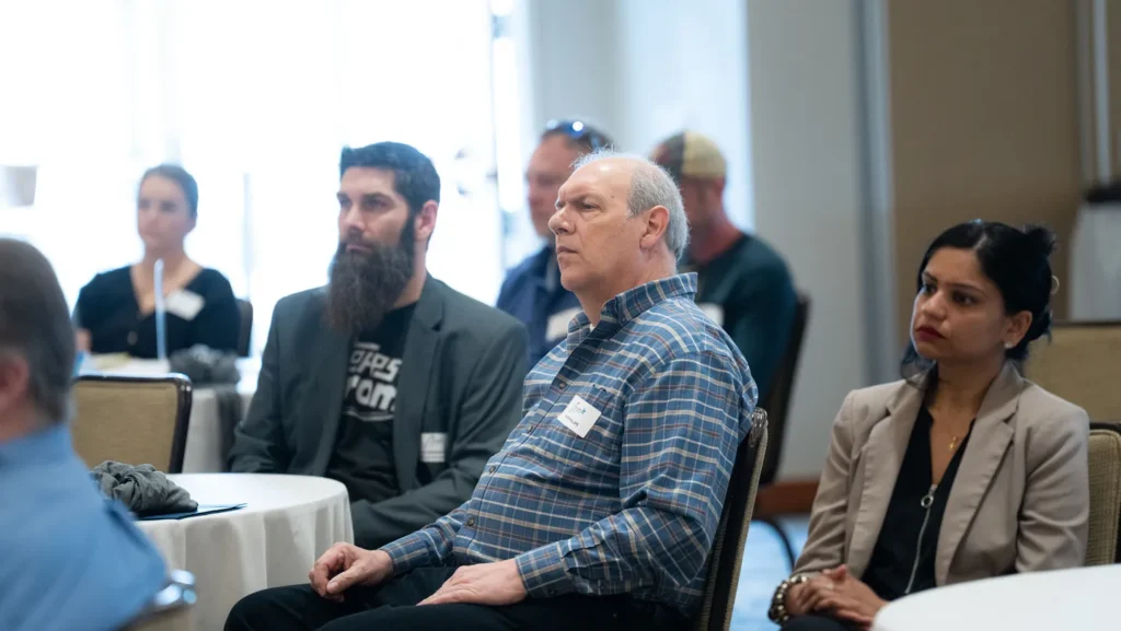 Diverse group of adults attentively listening at a professional seminar in a conference room.
