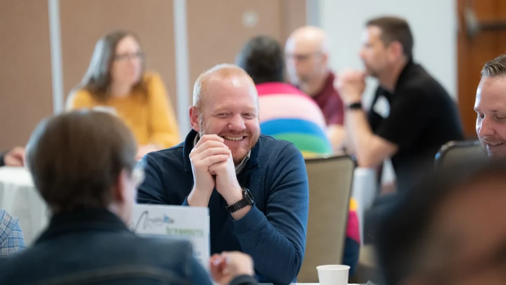 Group of professionally dressed adults engaged in discussion at a conference setting.