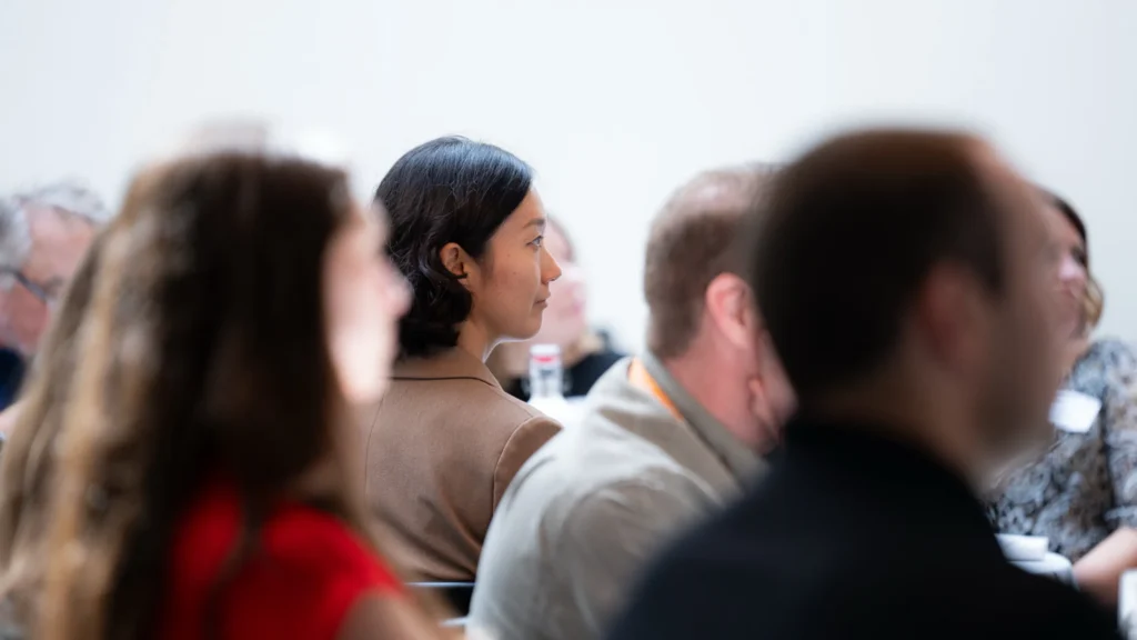 Diverse group of professionals attentively listening in a bright conference room.