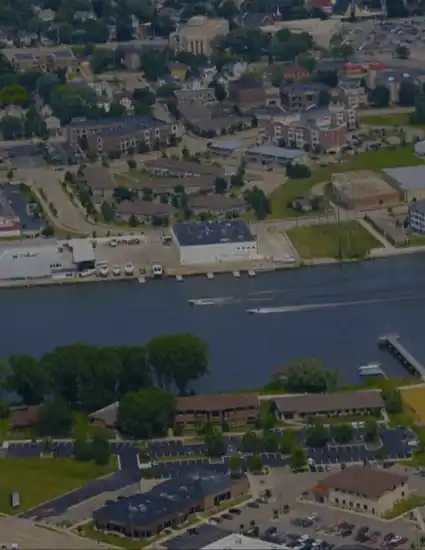 Aerial view of a small town with a river, businesses, residential areas, and a water tower, showcasing a blend of urban and natural elements.