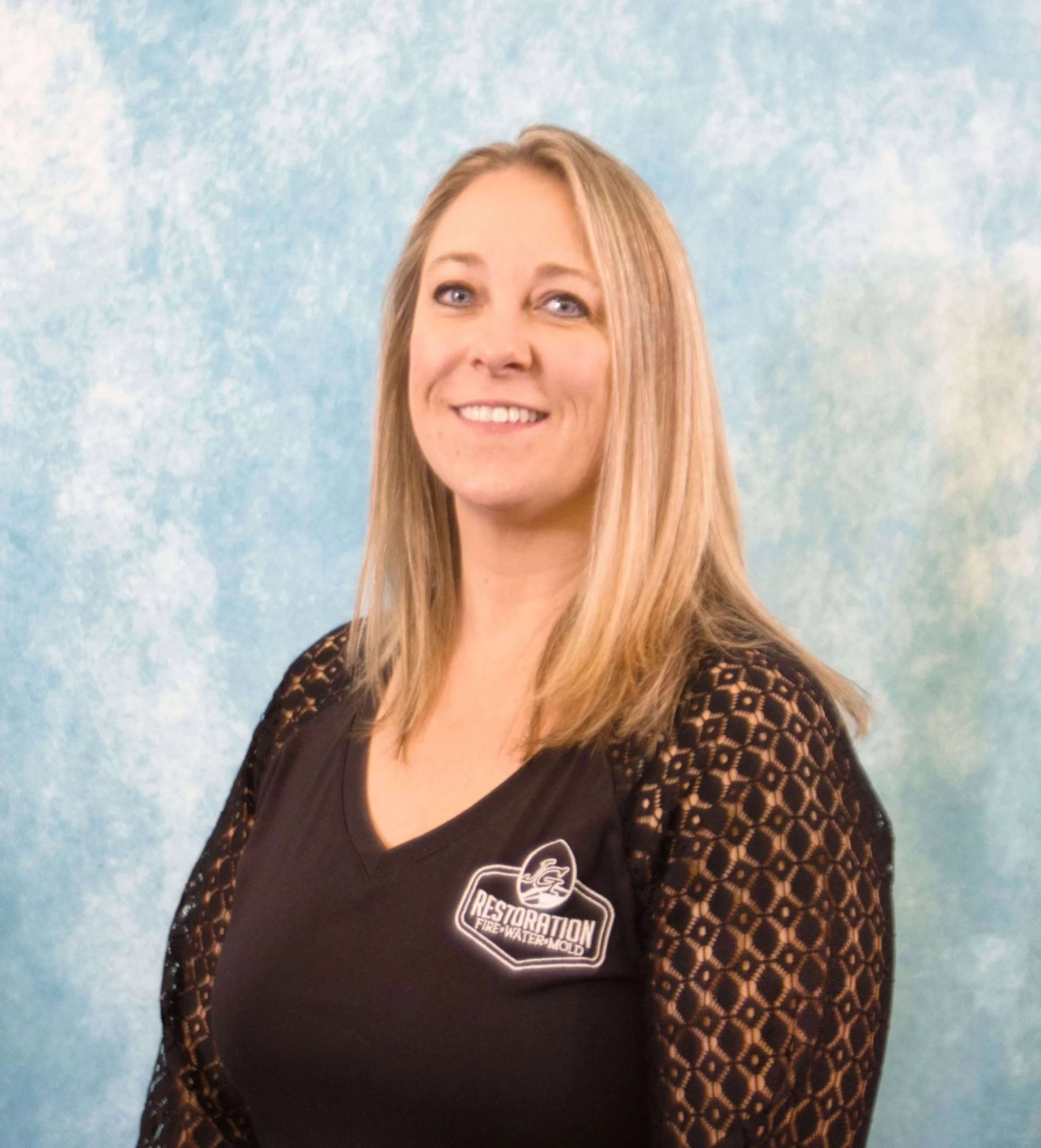 Professional portrait of a smiling woman with blonde hair wearing a black Restoration Fire Water Mold shirt.