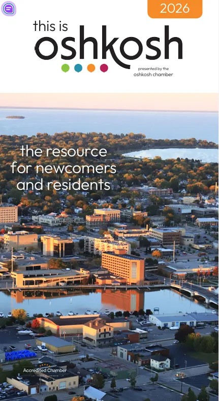 Aerial view of Oshkosh cityscape with buildings, water, and trees at sunset.